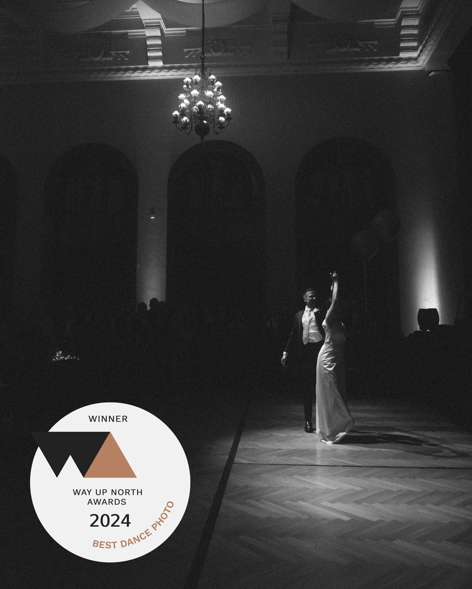 Black and white photo of couple sharing first dance in elegant ballroom, winner of Best Dance Photo at Way Up North Awards 2024.