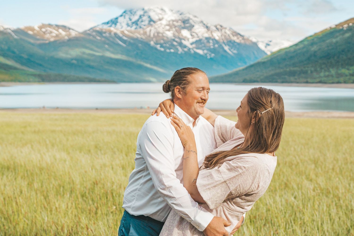 A young family shares a tender moment outdoors at golden hour, with parents gazing lovingly at their toddler son.