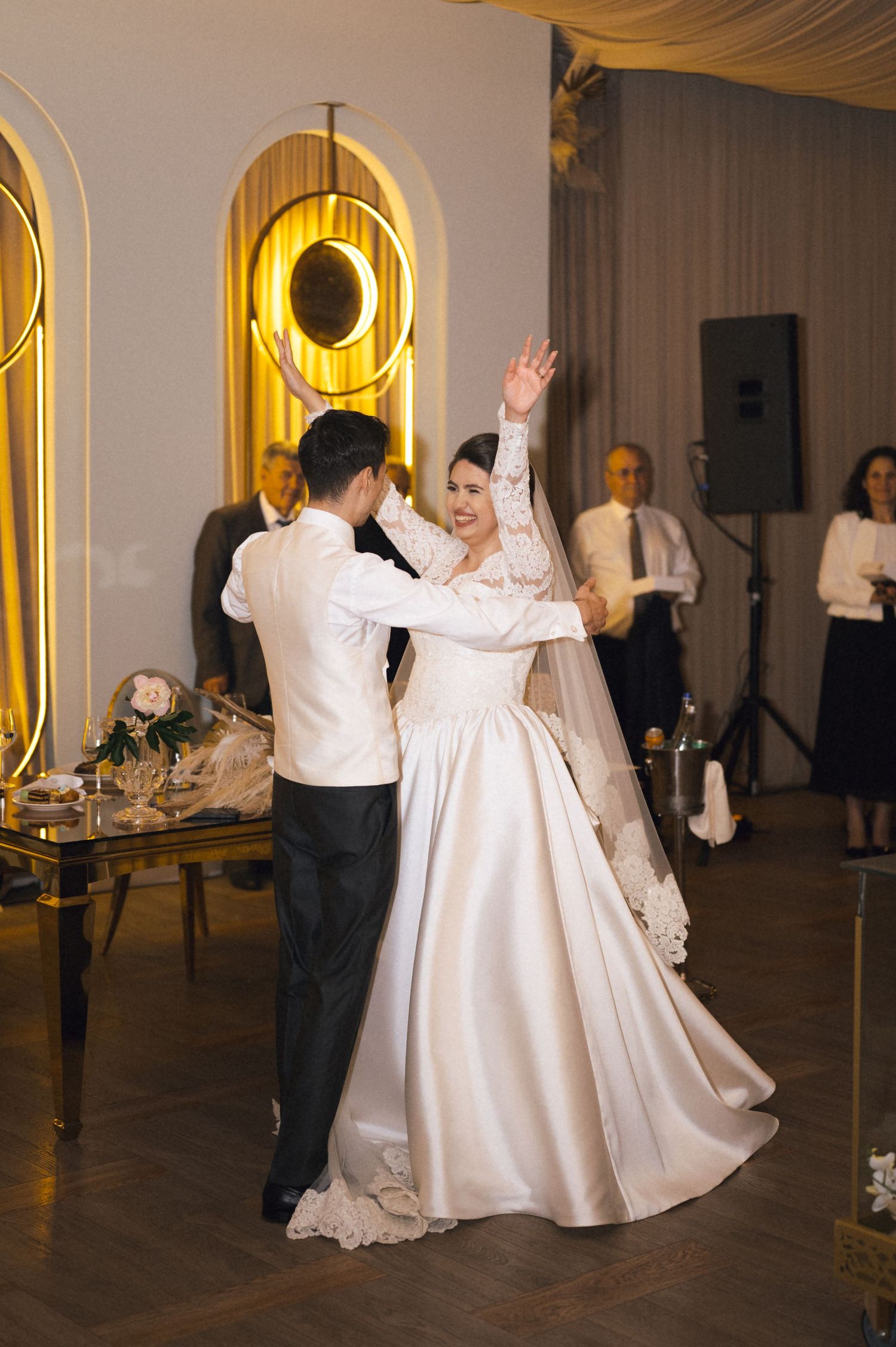 Bride and groom share their first dance at elegant wedding reception with gold arch decor.