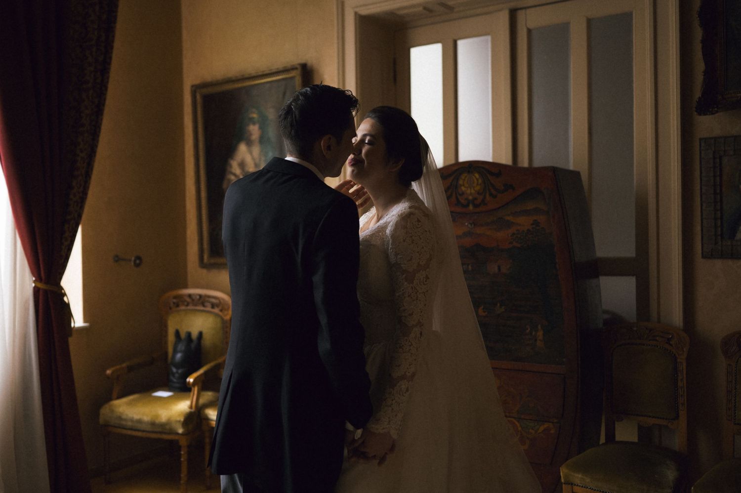 A bride and groom share a romantic moment in an elegantly decorated room during their wedding ceremony.