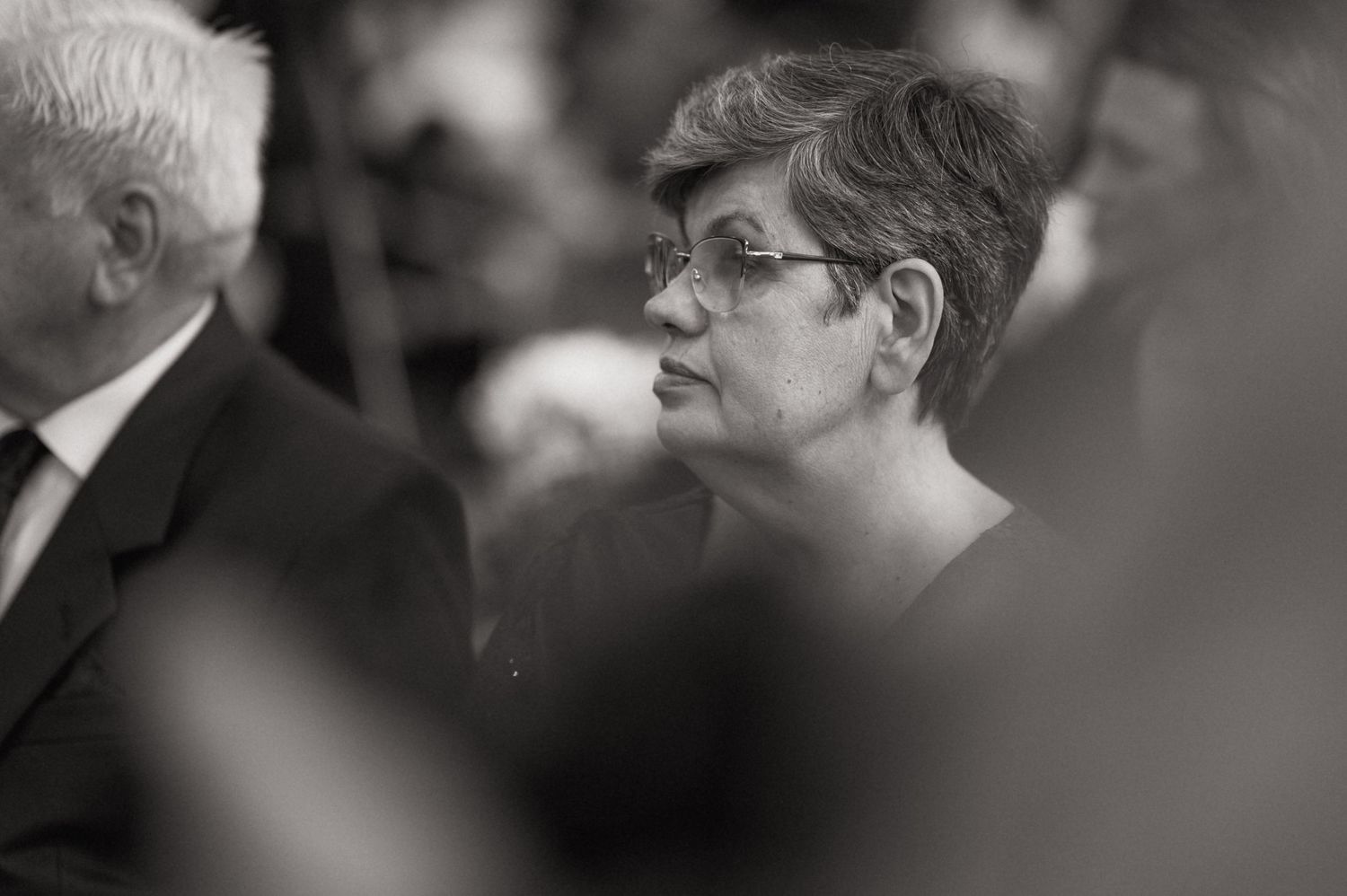 Black and white portrait of an elderly woman with short hair and glasses at a formal event.