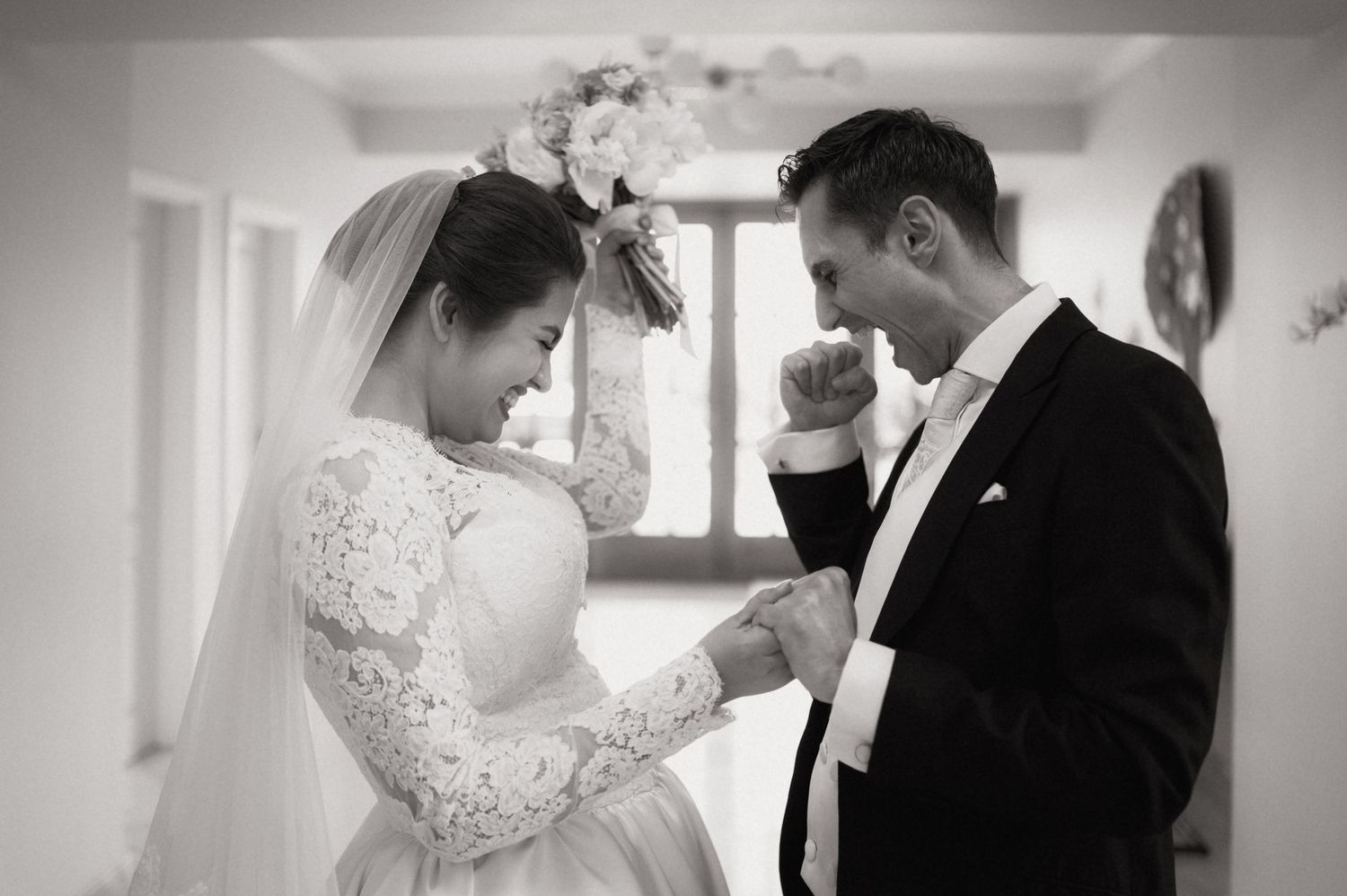 Black and white photo of bride and groom exchanging rings during an intimate wedding ceremony moment.