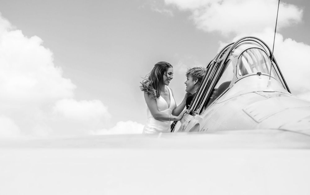 Black and white photo of a couple sharing a romantic moment on a sailboat deck under a cloudy sky.