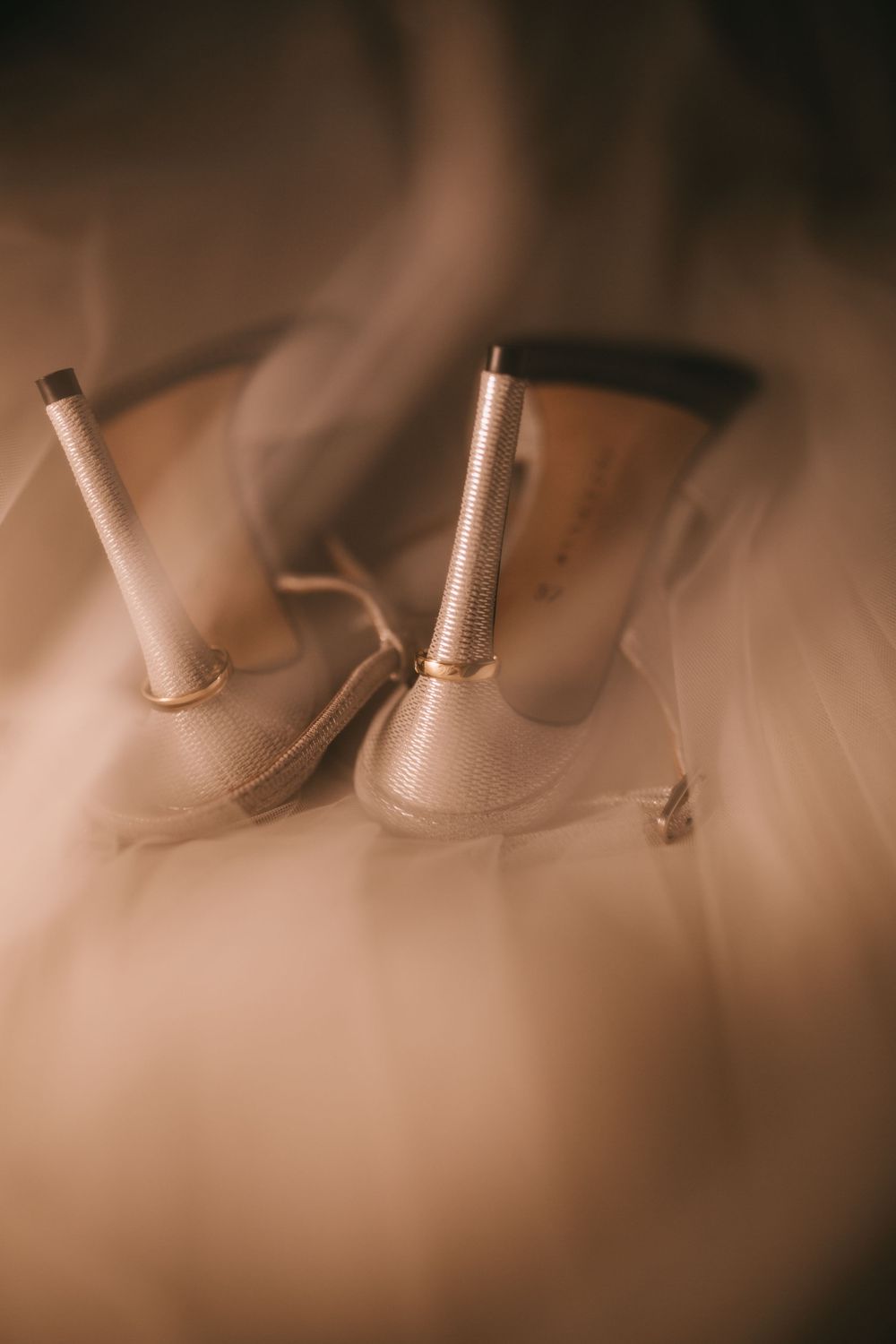 Close-up of elegant cream high-heel shoes with gold accents surrounded by soft, dreamy smoke on a warm background.