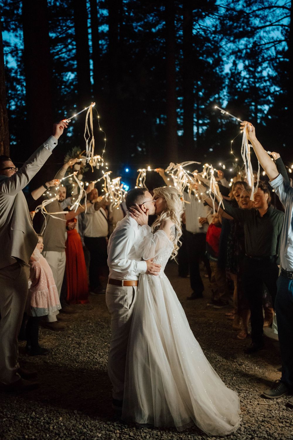Bride and groom share a romantic kiss during a sparkler send-off at their outdoor nighttime wedding celebration.