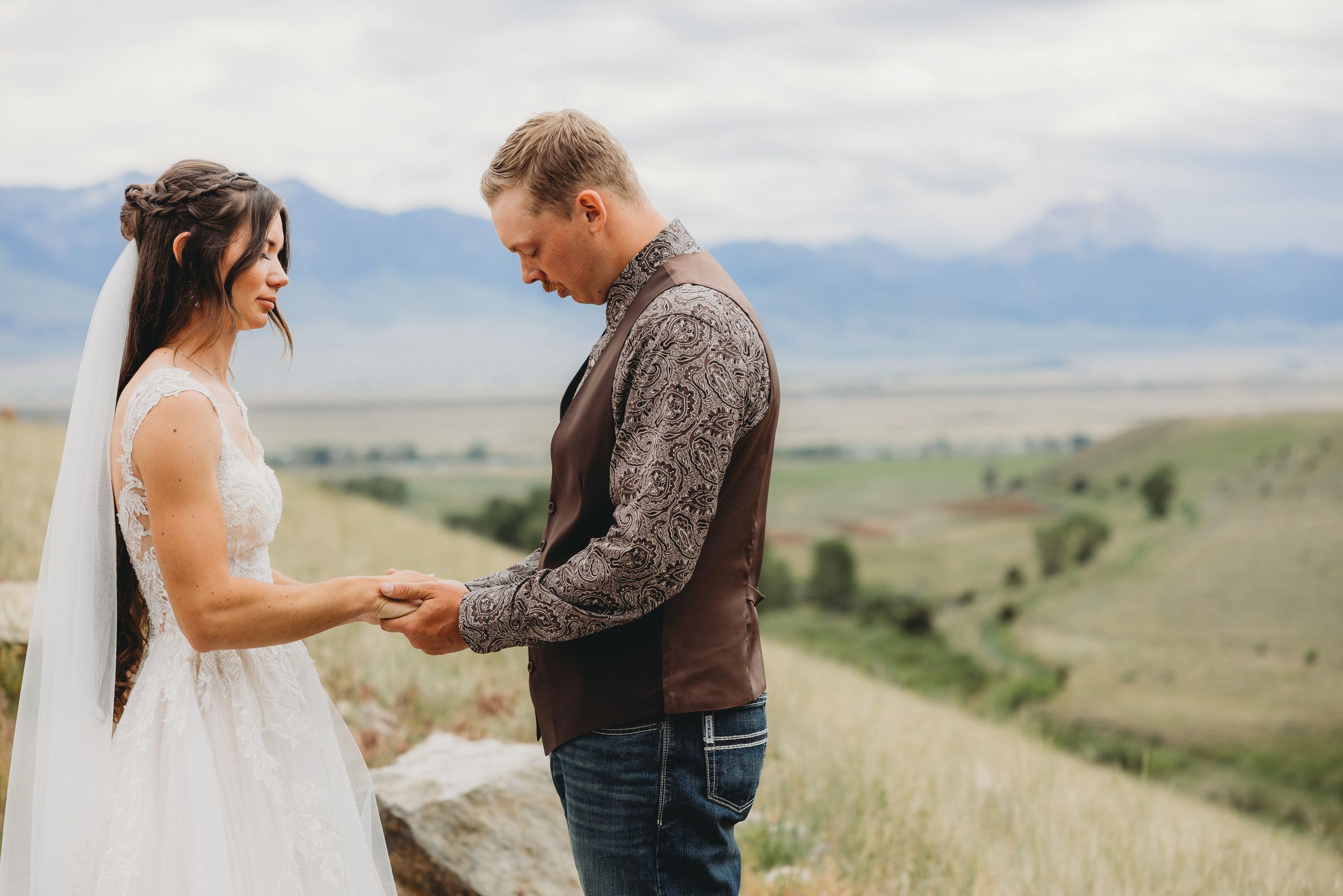 Bride and groom exchange vows outdoors with scenic mountain valley backdrop on their wedding day.