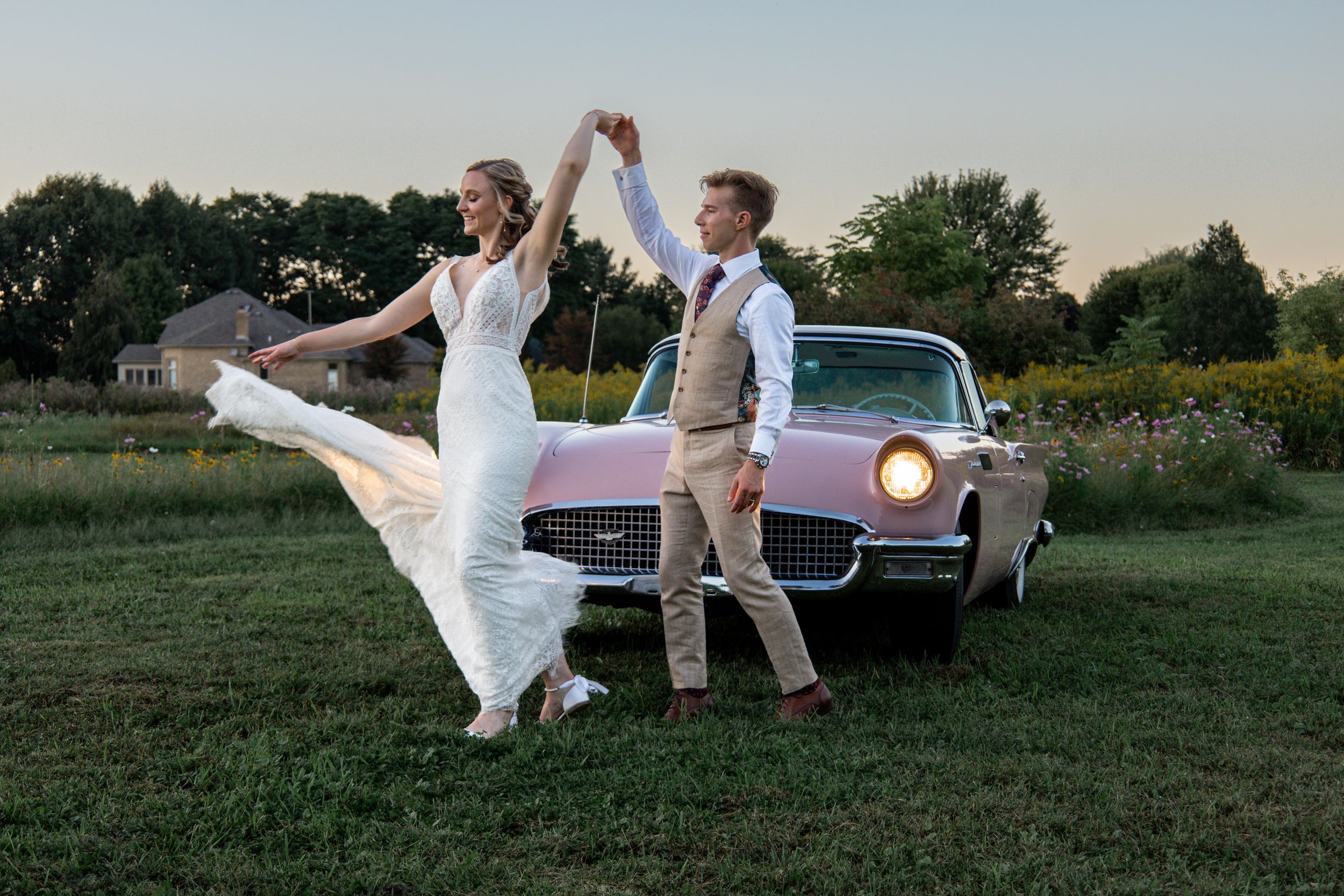 Bride and groom spinning in front of vintage car