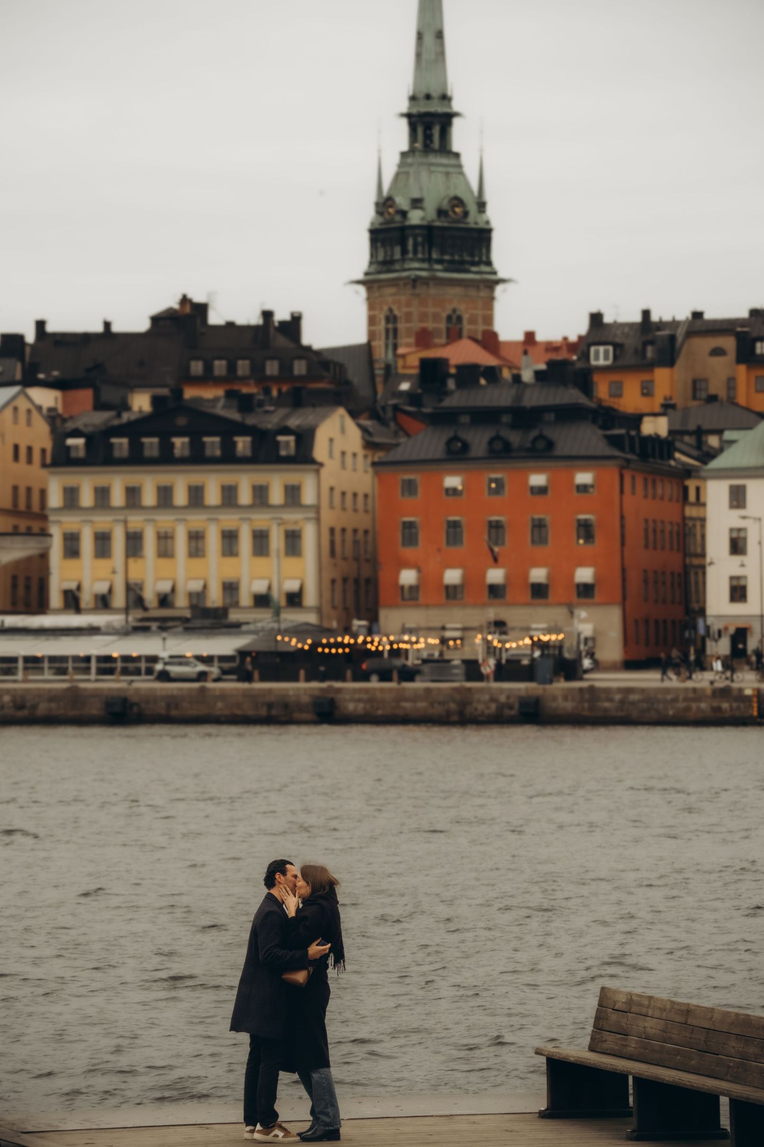 couple kissing at Skeppsholmen during surprise proposal while being captured by candid couple photographer in Stockholm
