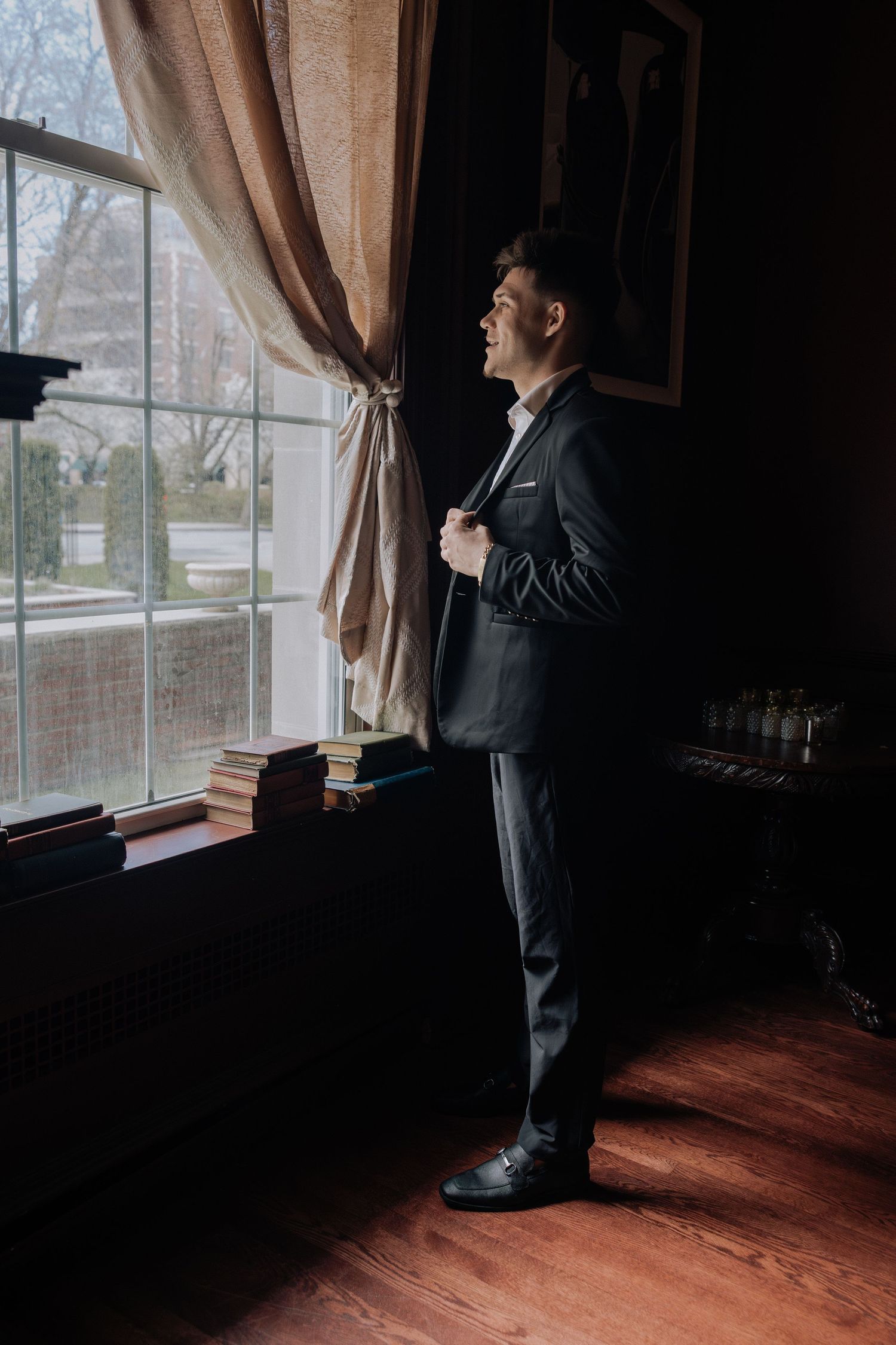 Groom adjusting suit by window at The Inn on Broadway Rochester NY