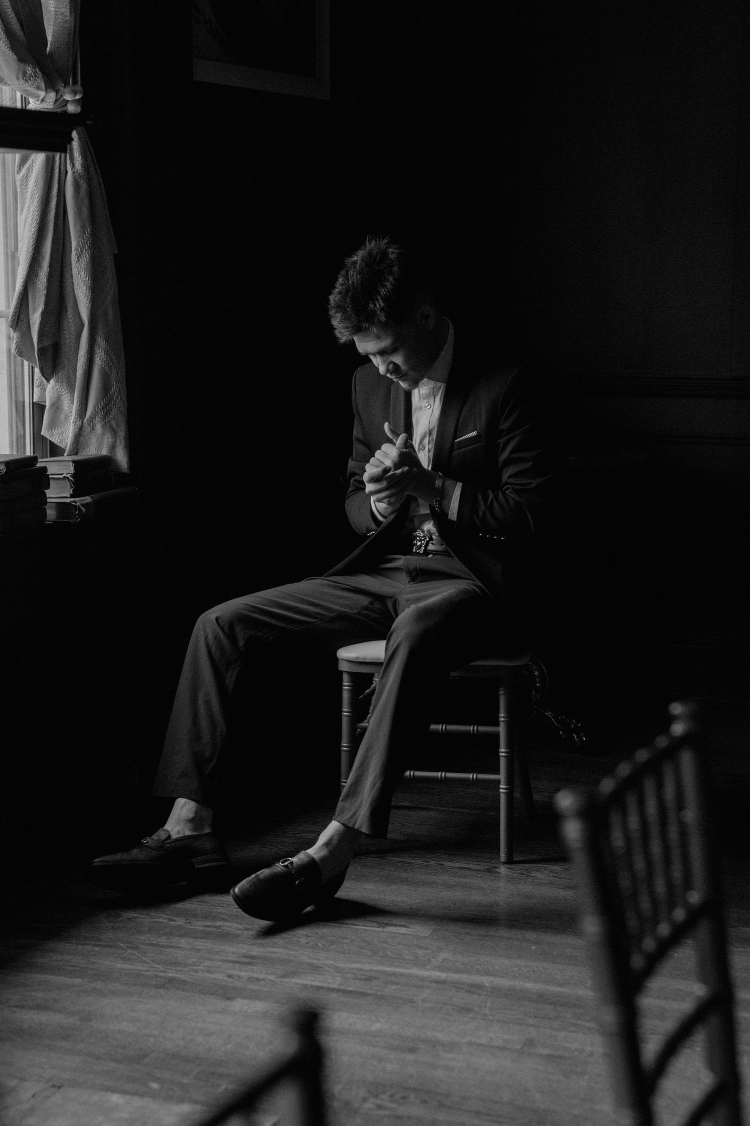 Groom sitting by a window in natural light at the Inn on Broadway in Rochester, NY