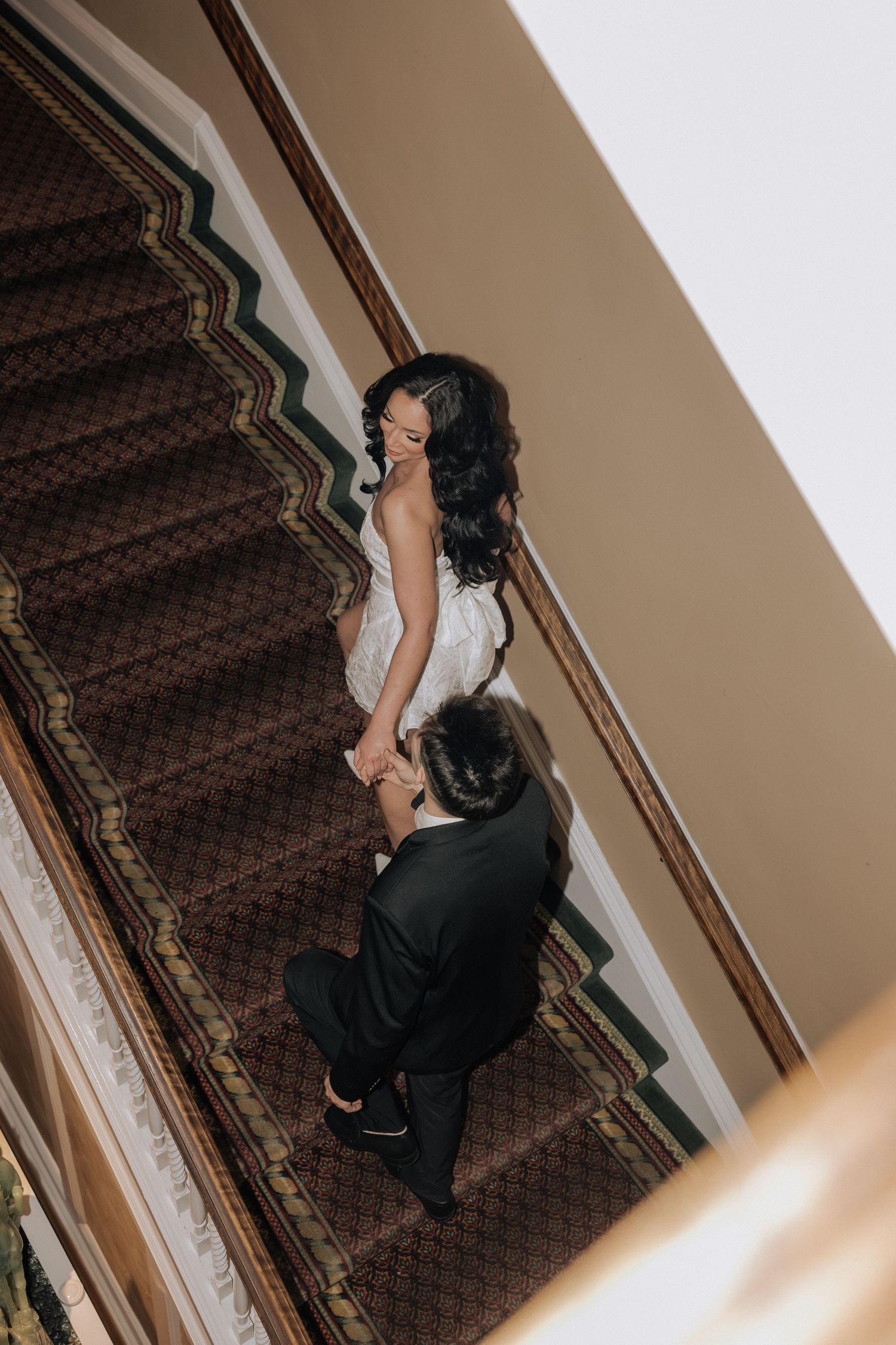 Couple walking up stairs during a romantic engagement session in Rochester
