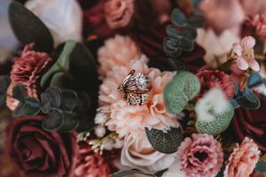 Rose gold diamond engagement ring nestled in a bouquet of pink and mauve wedding flowers.