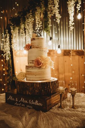 Three-tier semi-naked wedding cake with roses on a wood slice for Mr. & Mrs. Walker.