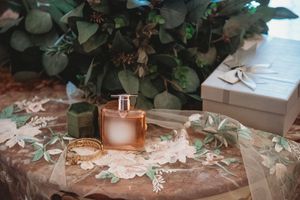 Bridal accessories flat lay with perfume bottle, gold bracelet, and eucalyptus greenery.