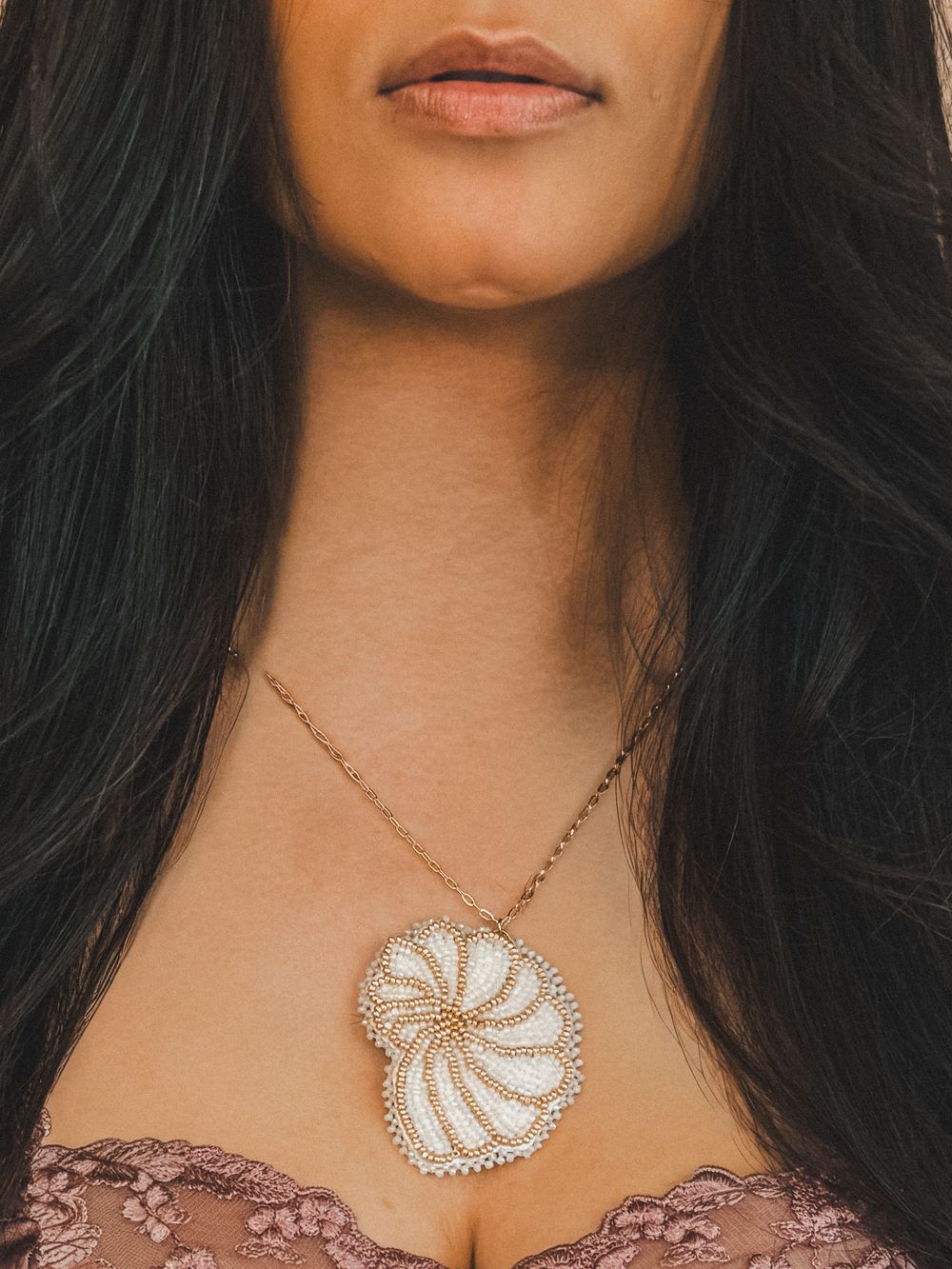 Close-up of a woman wearing a gold nautilus shell pendant necklace with crystal details on a delicate chain.