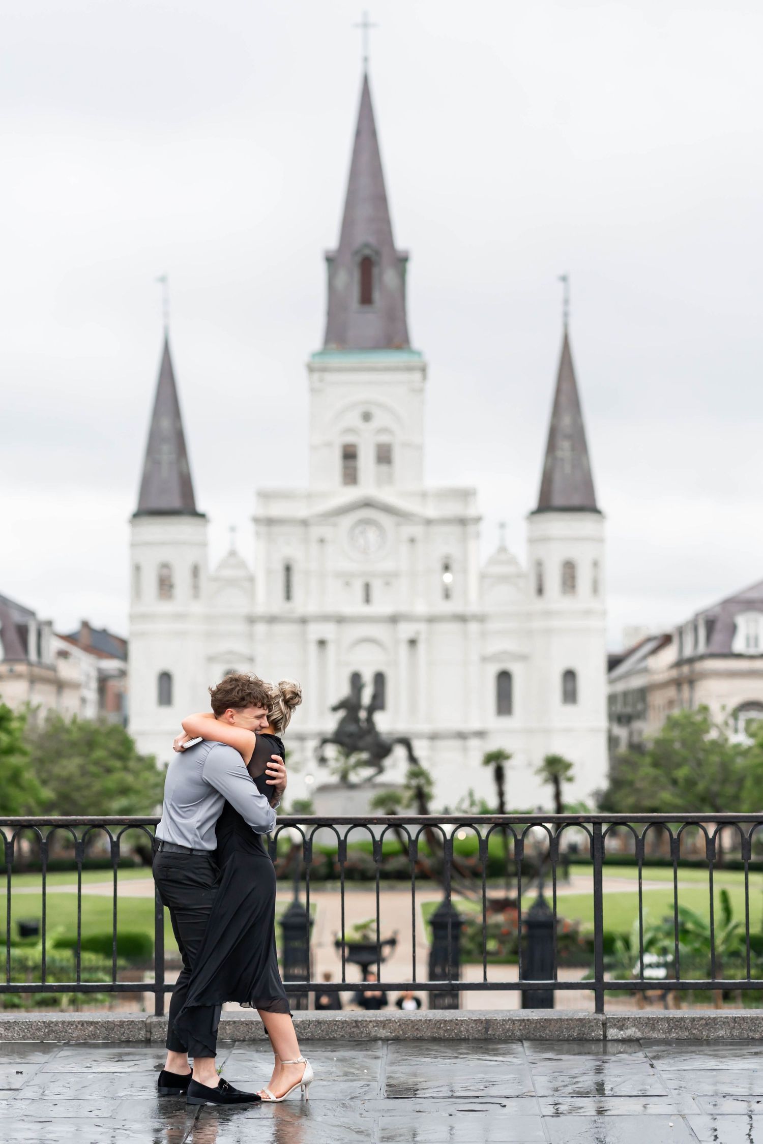 engaged couple hug in front of the st louis cathedral in new orleans