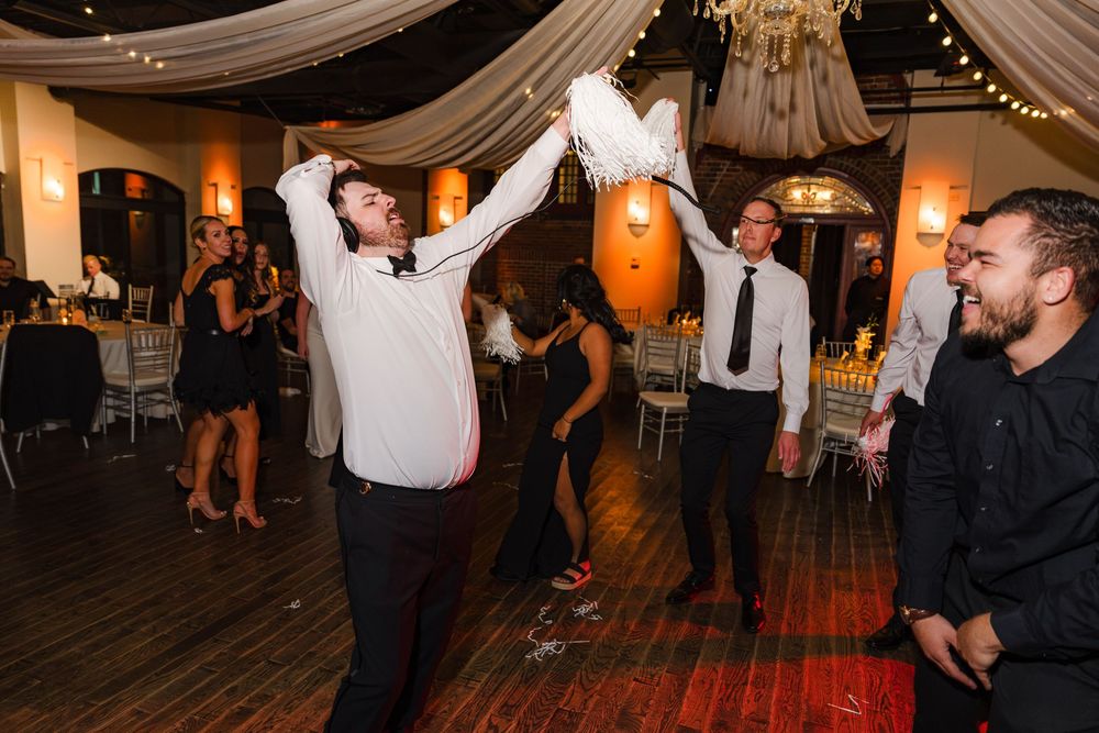 Guest energetically dancing and tossing a white item at a lively wedding reception.