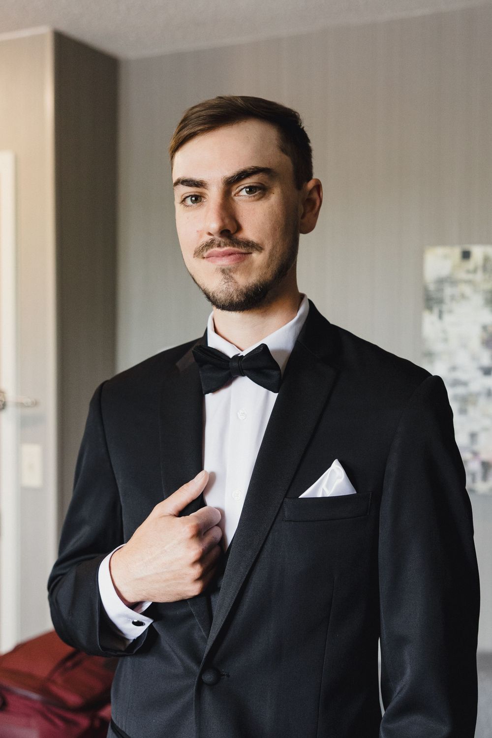 Close-up shots of groom in black tuxedo with bowtie and white pocket square.