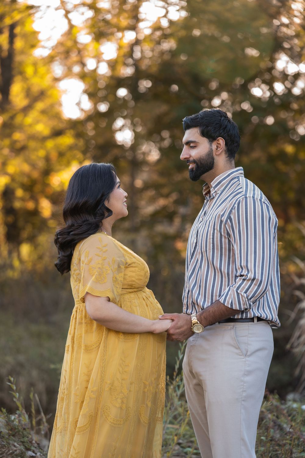 A couple in yellow dress and striped shirt share intimate moments outdoors during golden hour in autumn.