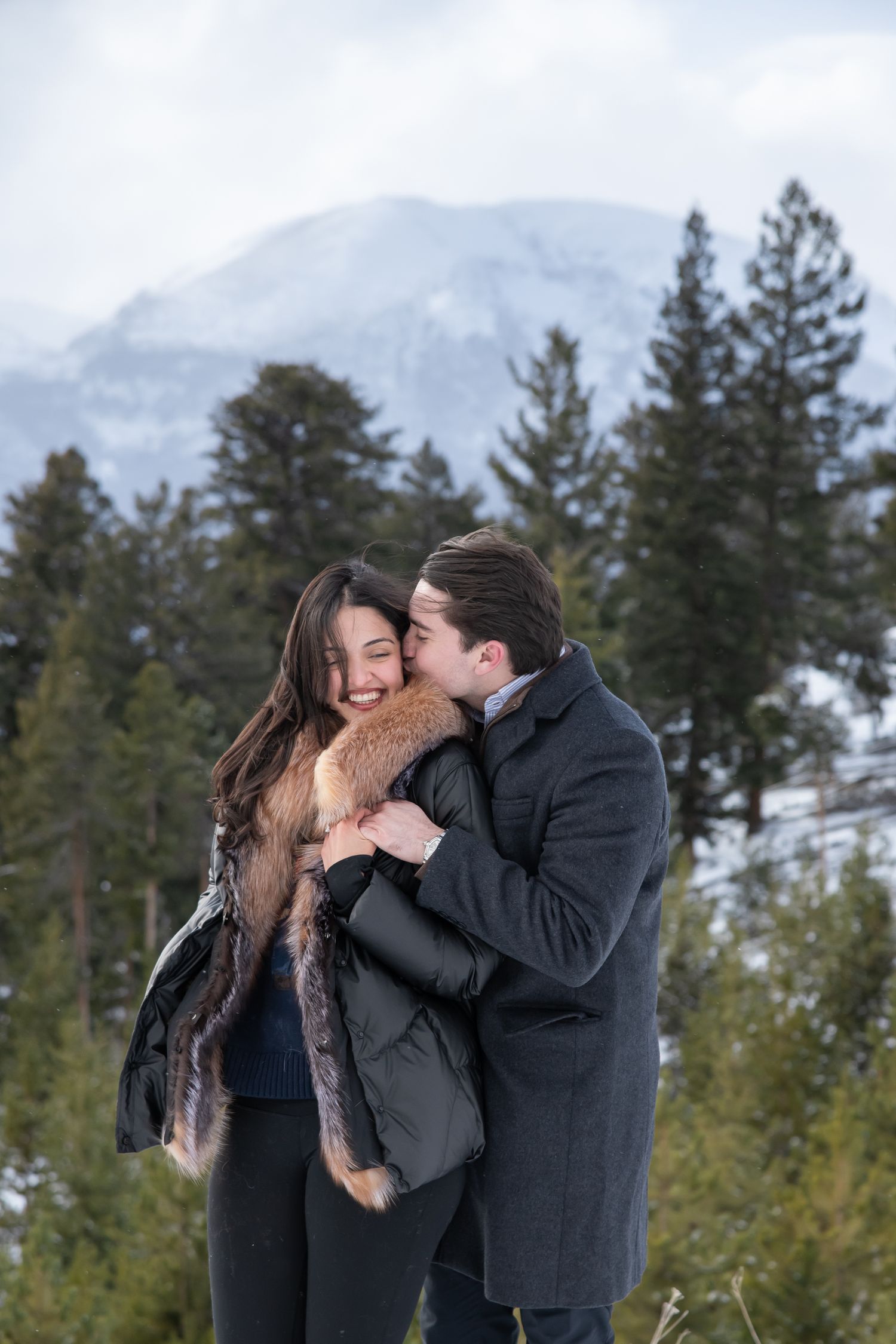 Romantic moment in front of a scenic mountain landscape with evergreen trees in the background for Breckenridge engagement photo session.