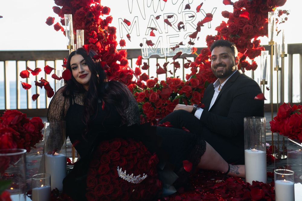 A wedding reception venue decorated with vibrant red floral arrangements and elegant table settings.