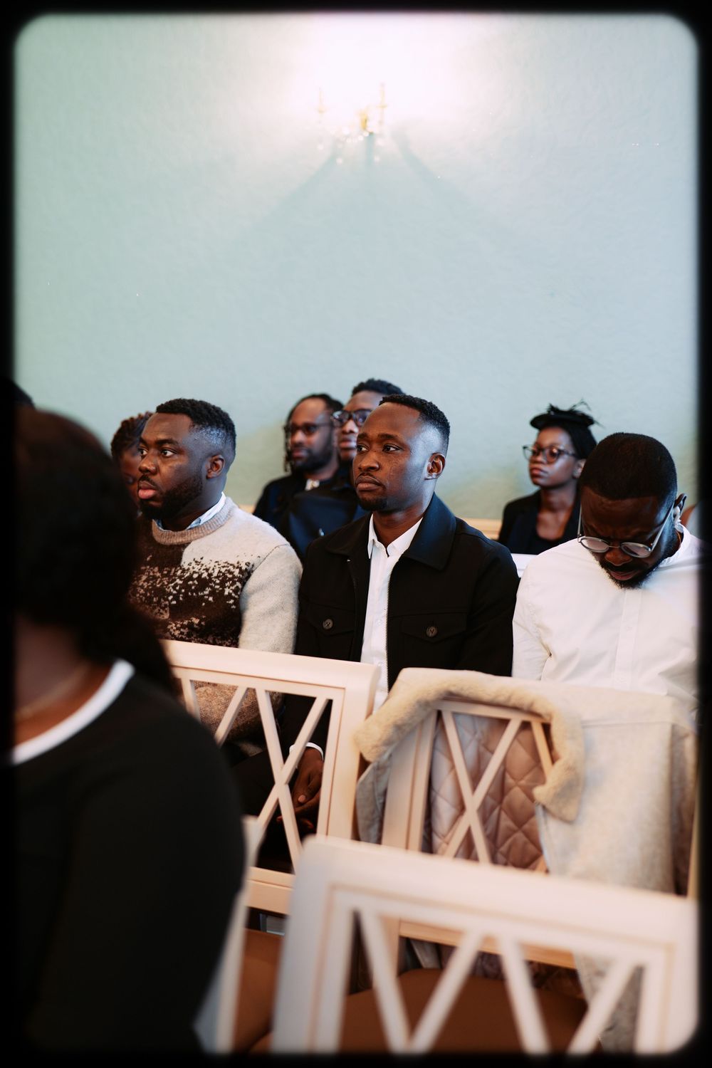 A group of people seated in white chairs at what appears to be a formal event or gathering.