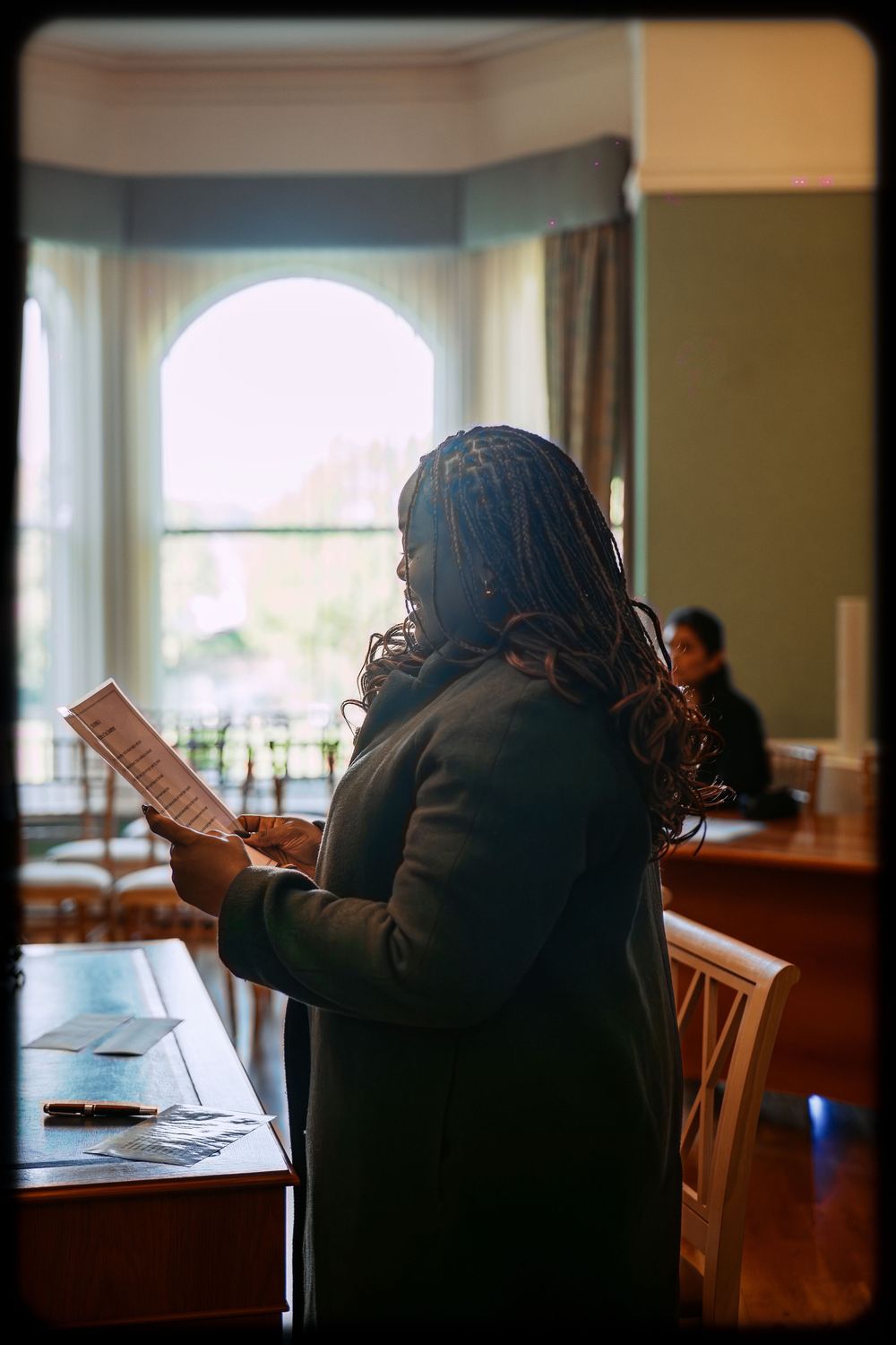 A series of silhouetted figures reading books in a sunlit room with windows.