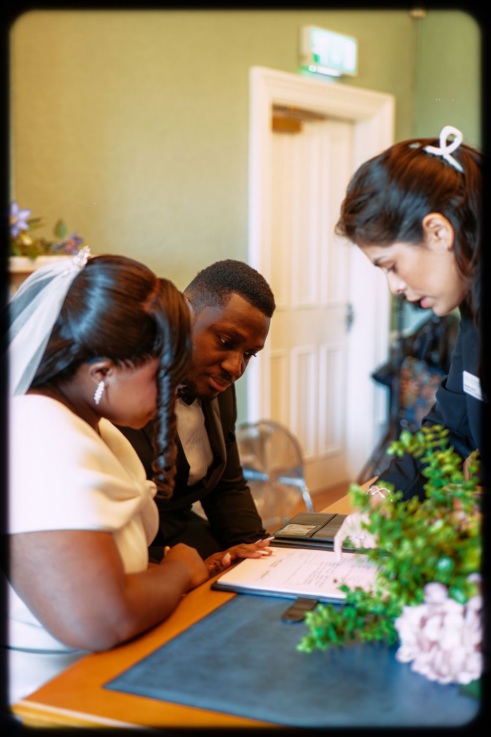 Students work together at a table with green plants visible in a classroom setting.