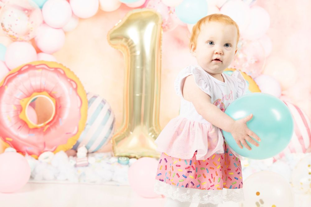 First birthday party setup with pink balloon decorations, gold number 1, and a turquoise balloon.