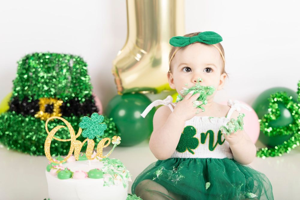 Green and gold St Patrick's Day themed party decorations and treats arranged on a white surface.