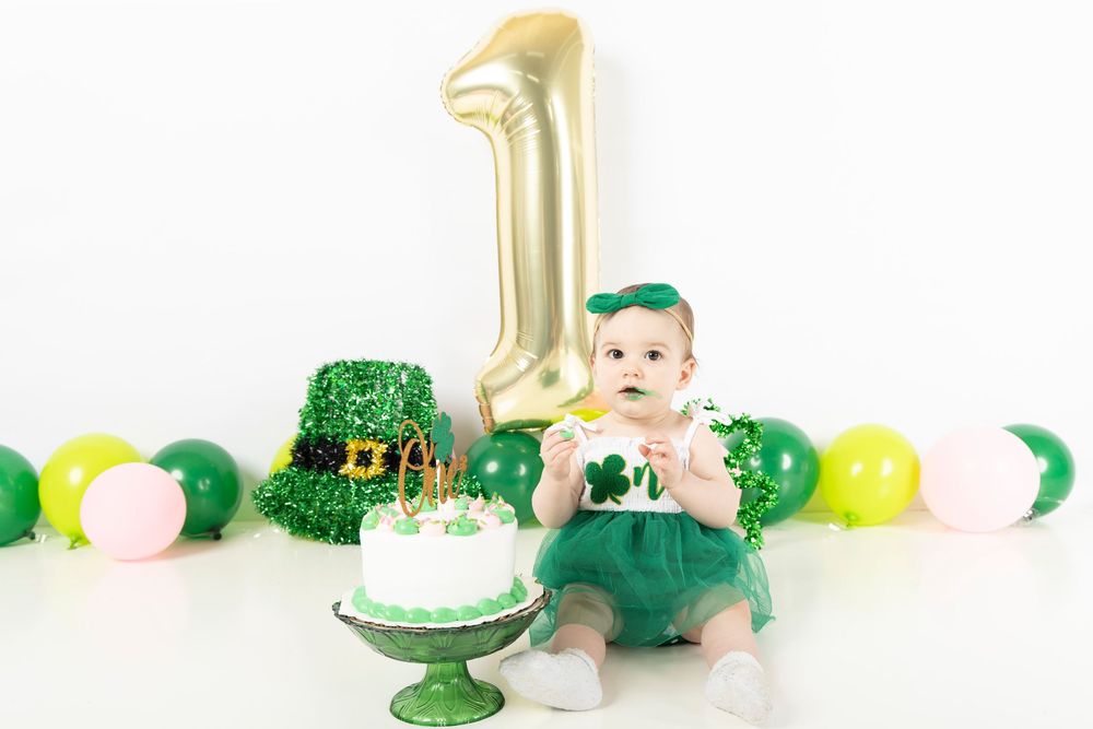 St Patrick's Day themed baby photo setup with green and gold decorations against white backdrop.