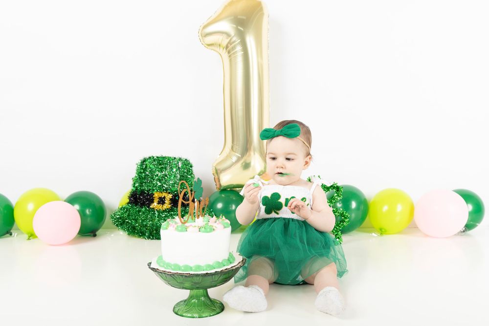 Green and gold St. Patrick's Day party decorations arranged on a white table with shamrock accents.
