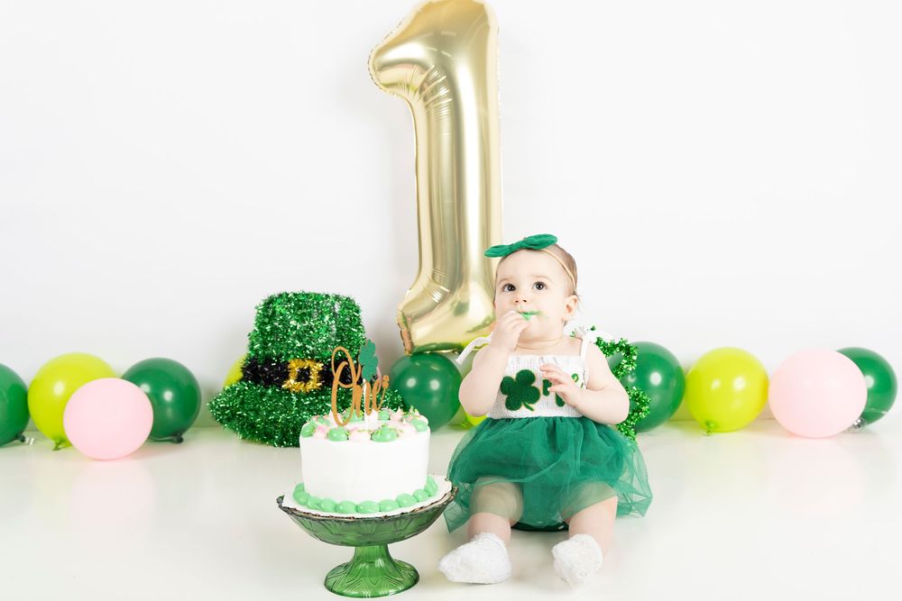 A St. Patrick's Day party table decorated with green and gold balloons, cakes, and shamrock decorations.