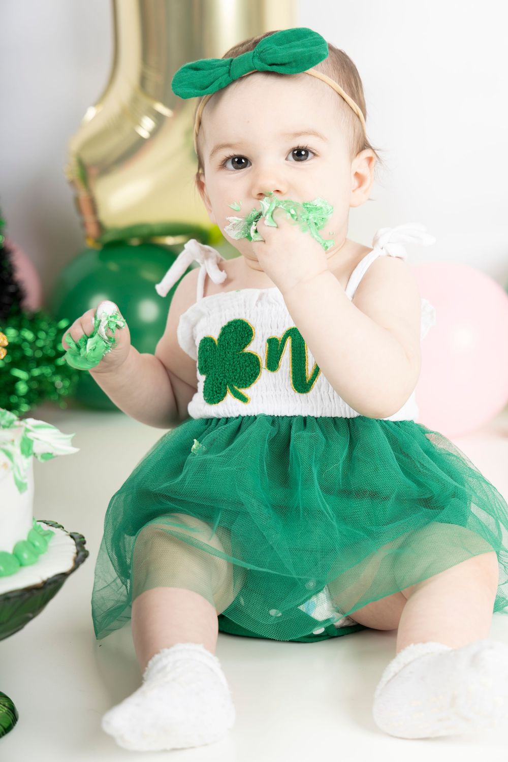 Baby wearing emerald green tulle dress with shamrock details for St. Patrick's Day celebration.