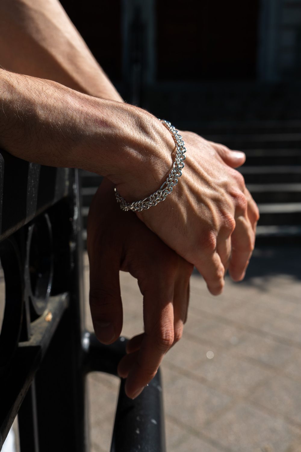Close-up shot of hands wearing silver jewelry reaching down towards a dark surface in sequence.