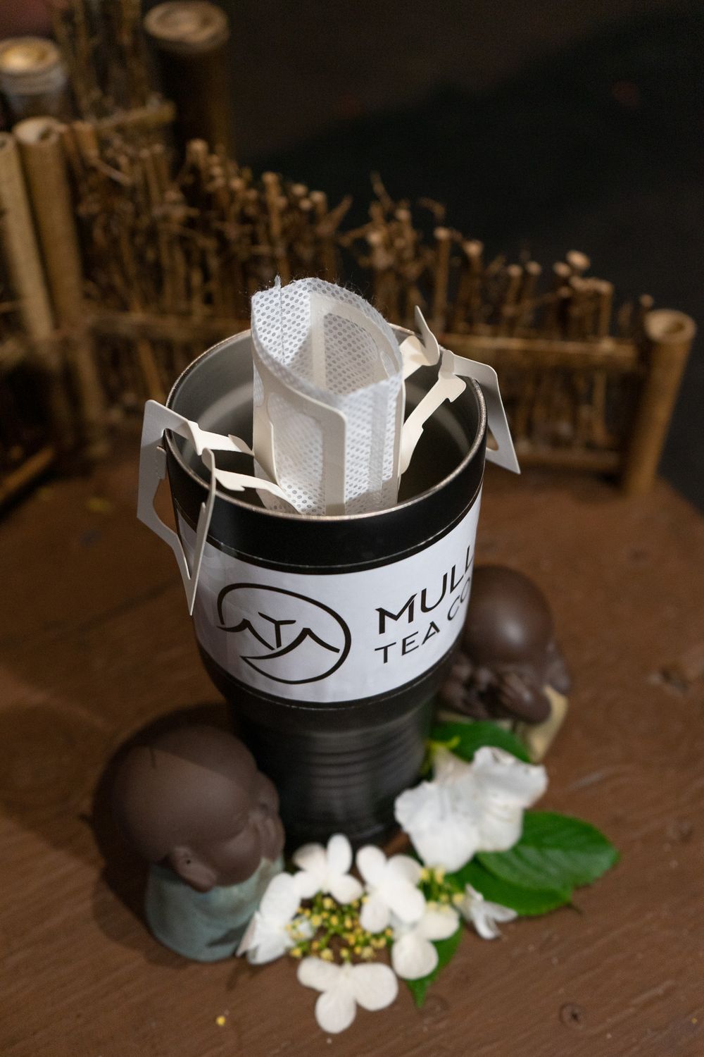 A series of four photos showing chocolate truffles and white flowers arranged next to a black container with a logo.