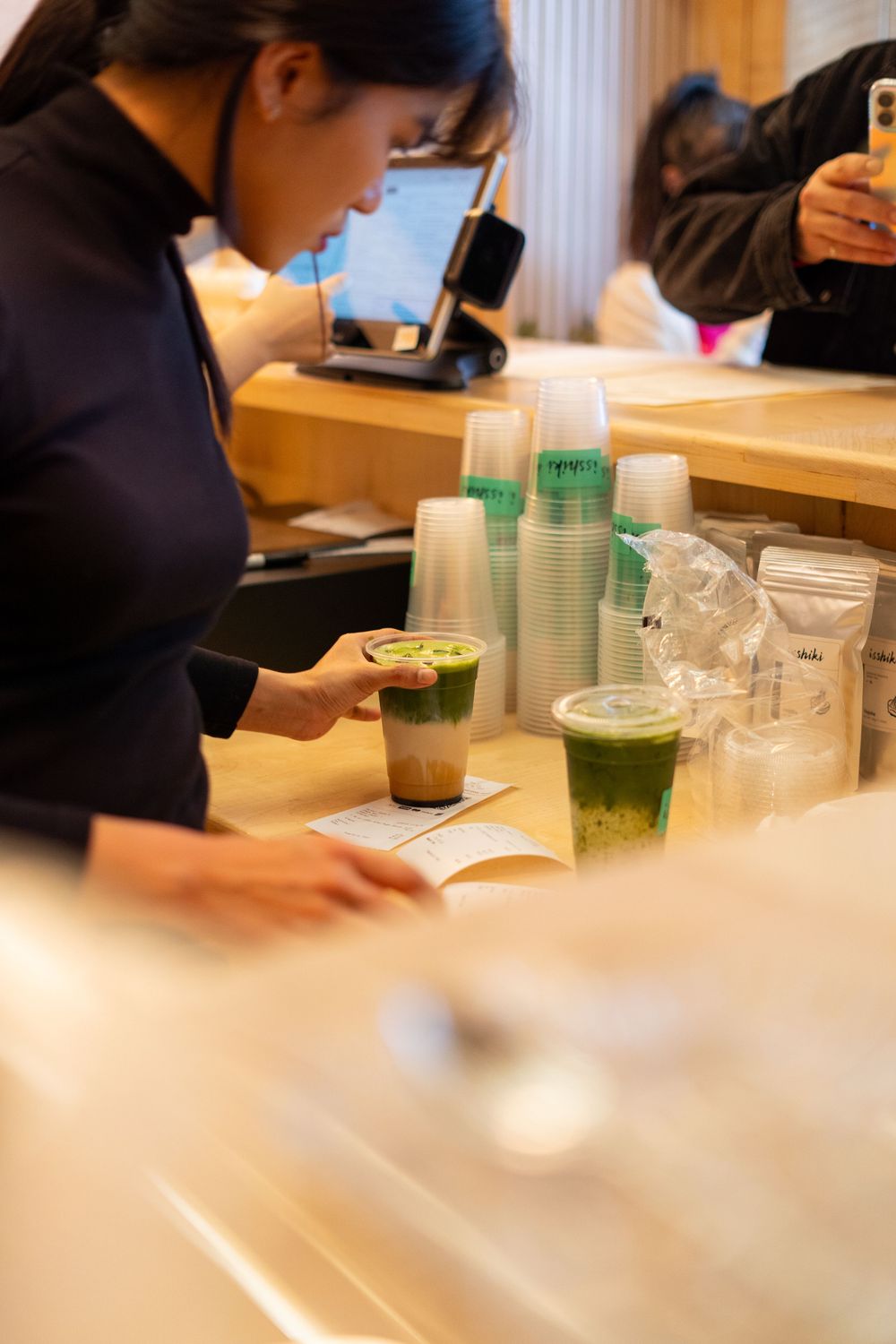 People studying at a cafe table with drinks and paper cups visible in a casual learning environment.