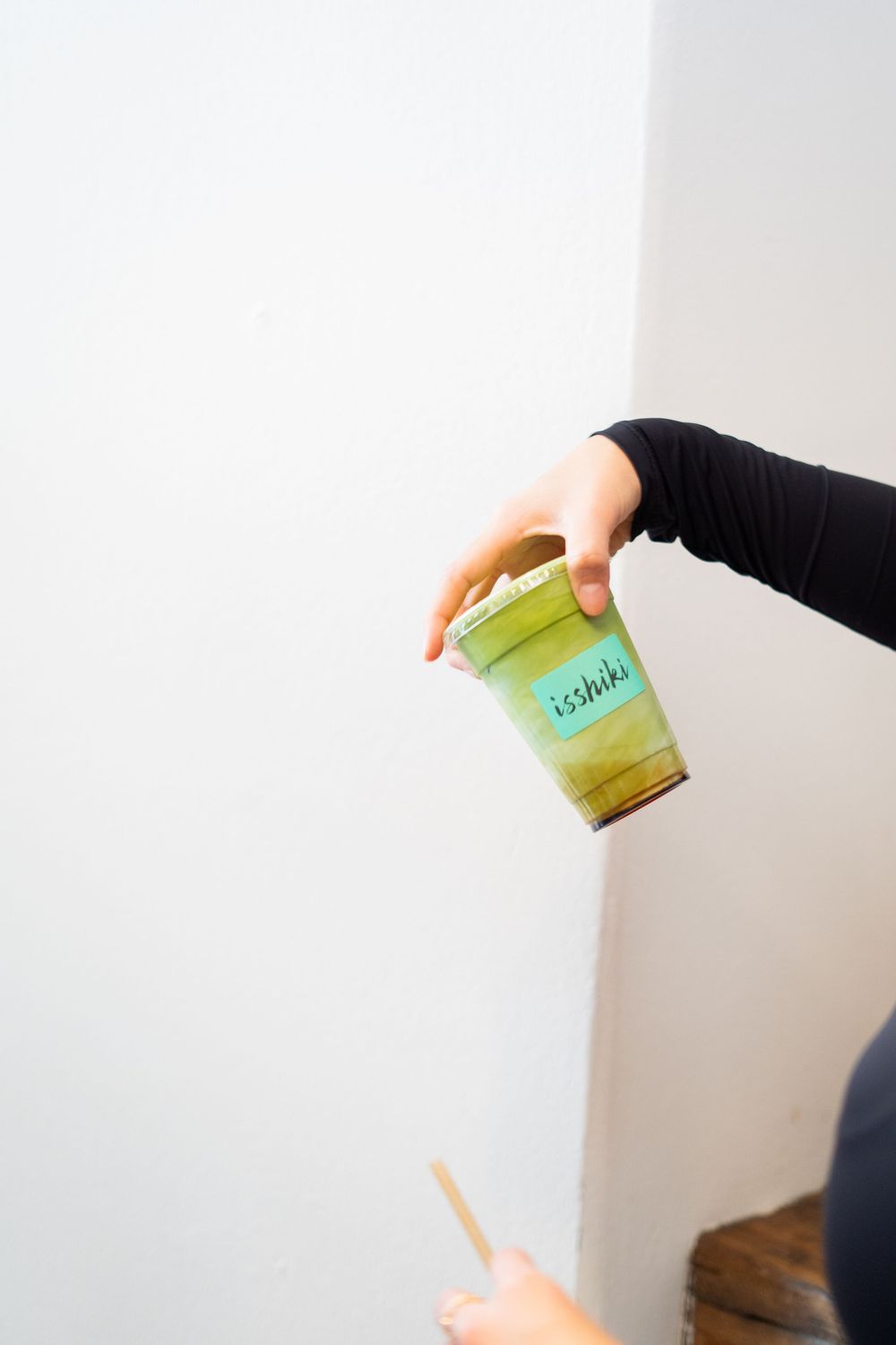 A hand holds a small green jar of baby food against a white background.