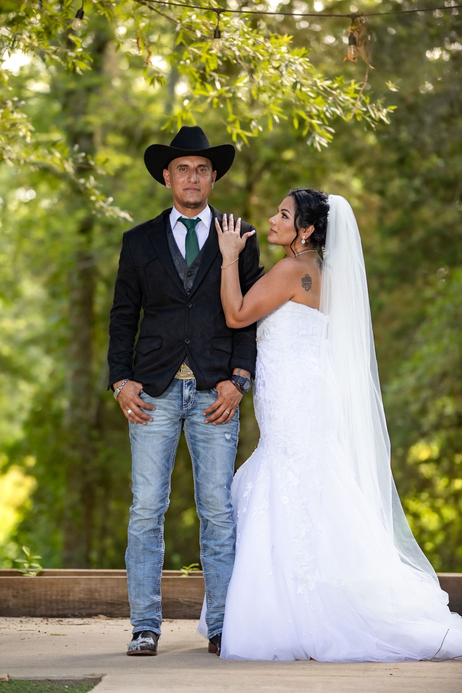 An elegant maternity portrait in a flowing blush pink tulle gown with sheer sleeves against a dark gray backdrop.