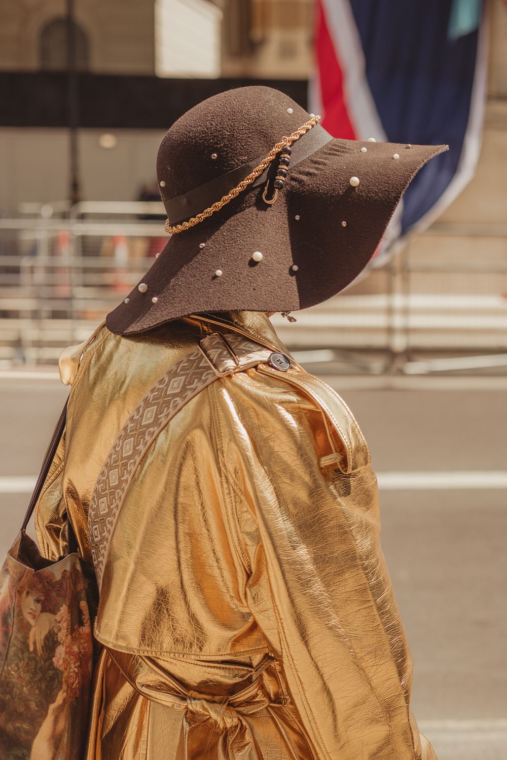 A woman wearing a gold coat with a wide brimmed brown hat
