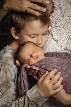 Newborn session family photo sibling snuggling baby girl