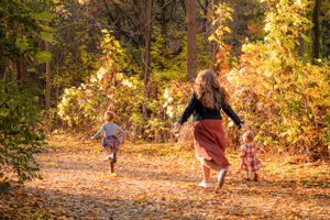 Fall Family session mommy funning through leaves with daughters