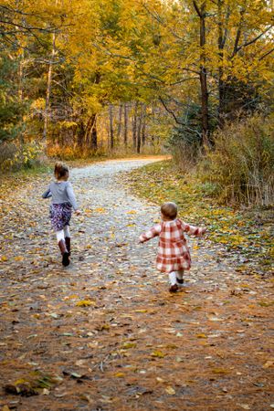 Fall Family session sisters running along pathway covered in leaves