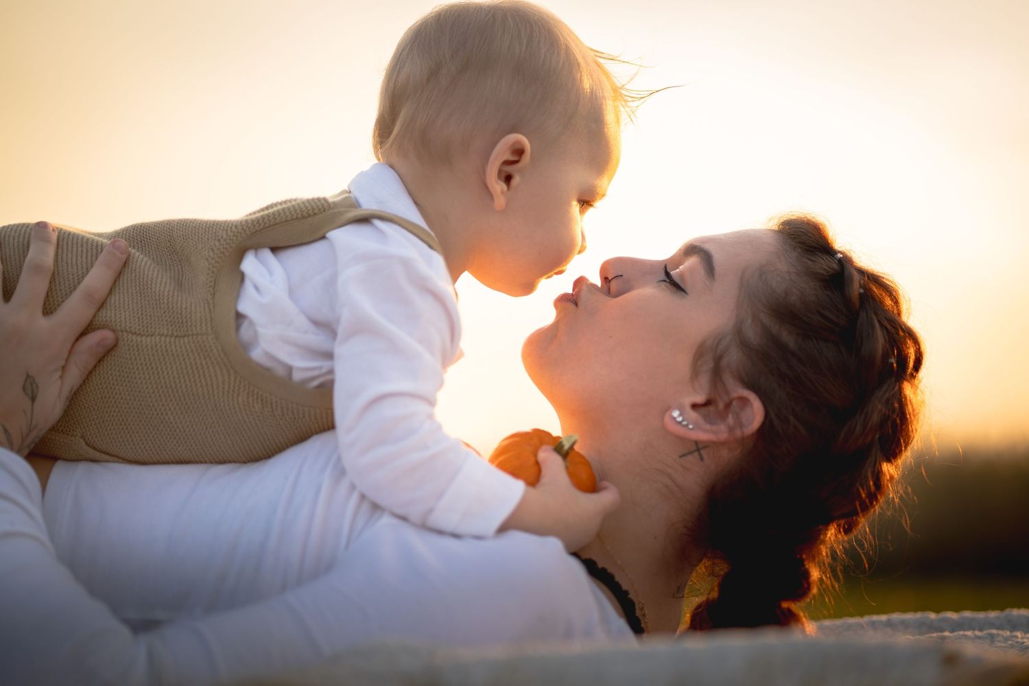Parent and child play together in a sunlit field during golden hour, creating joyful silhouettes against the sunset.