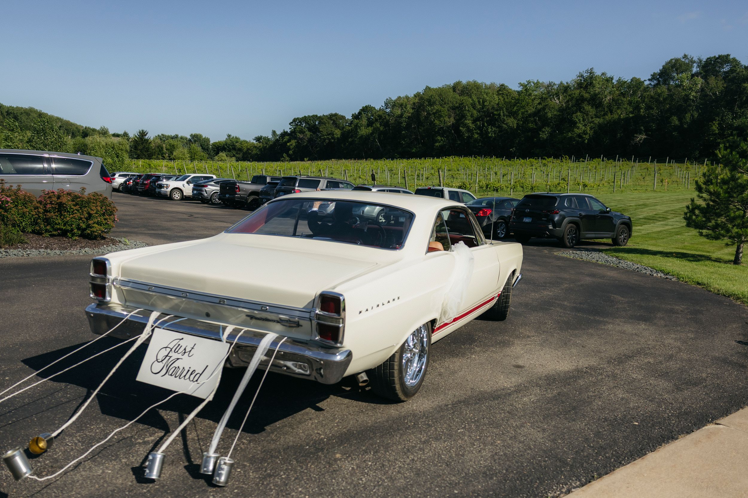 Chicago wedding couple traveling between locations in Classic white Ford Fairlane with 'Just Married' sign and tin cans tied to the back