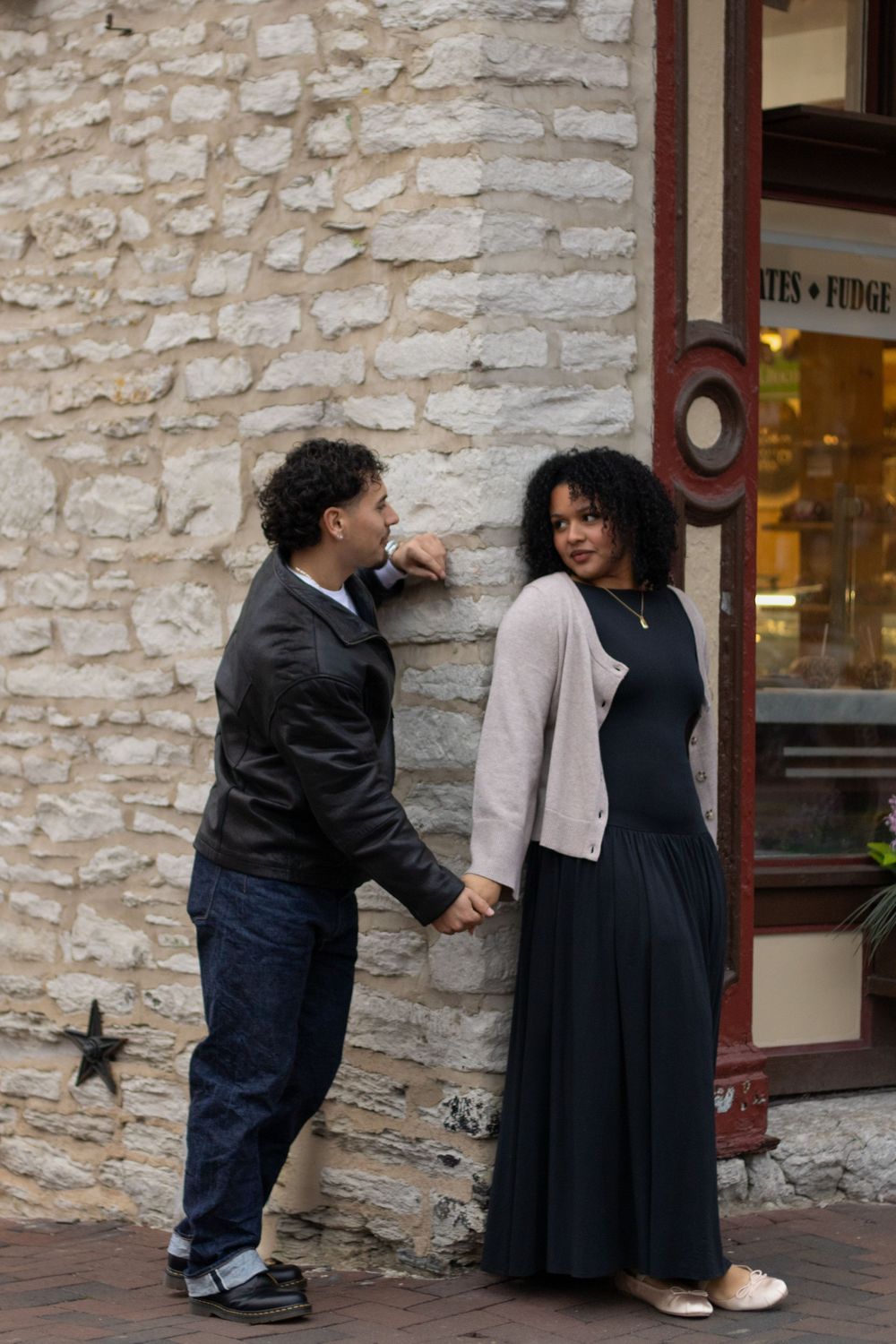 Two people share a tender moment against a textured stone wall background.