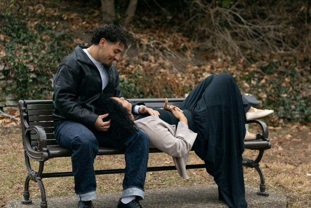A couple sits together on a park bench having an intimate conversation.