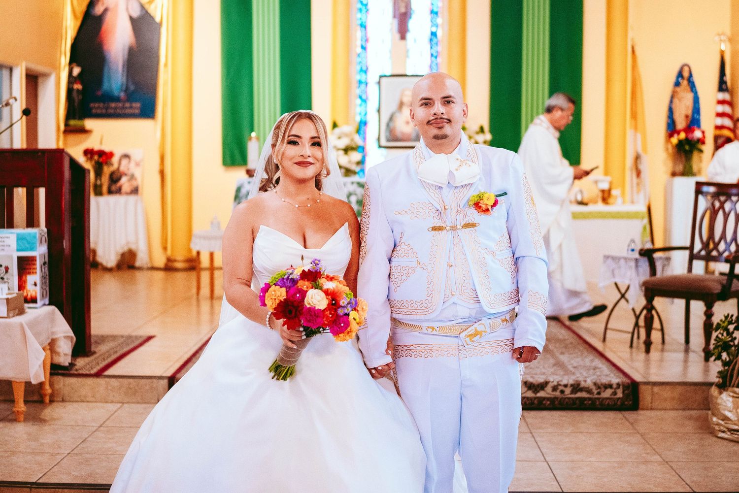 Wedding couple and guests celebrate in a beautiful yellow-walled venue with green trim and elegant decor.