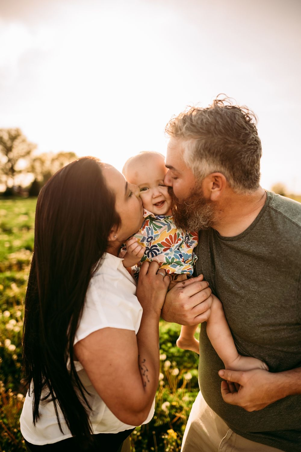 Tender family moment captured during golden hour in a sunlit field.