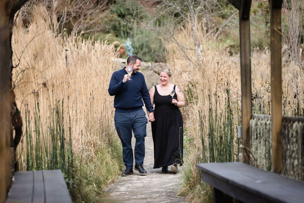 A couple walks together along a tree-lined path in a natural outdoor setting.